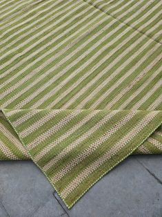 a green and beige striped rug on the ground