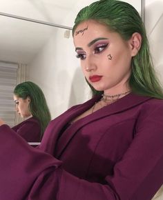 a woman with green hair and makeup is taking a selfie in front of a mirror