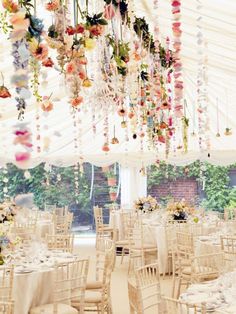 the inside of a marquee decorated with flowers and chandeliers for a wedding reception