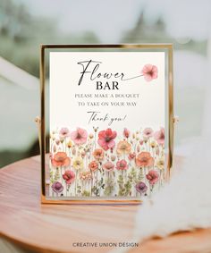 a flower bar sign sitting on top of a wooden table