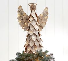 an angel statue on top of a christmas tree decorated with lights and tinsels