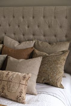 a bed topped with lots of pillows on top of it's headboard and foot board