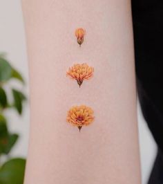 three small orange flowers on the back of a woman's right arm and leg