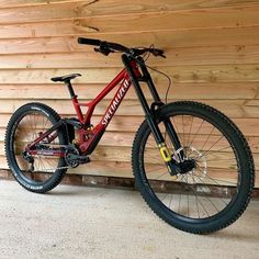 a red mountain bike parked in front of a wooden wall