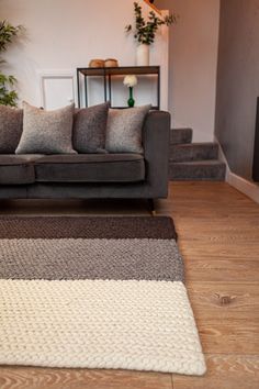 a living room filled with furniture and a rug on top of a hard wood floor