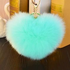 a green pom - pom keychain sitting on top of a table