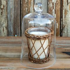 a glass jar with a candle inside on a wooden table