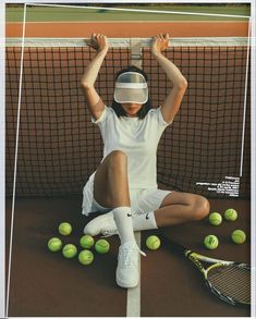 a woman sitting on the ground with tennis balls and racket in front of her