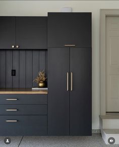 a kitchen with black cabinets and gold handles on the countertop, next to stairs