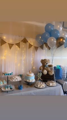 a teddy bear sitting on top of a table next to a cake and cupcakes