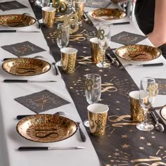 the table is set with gold and black plates, silver napkins, and glasses