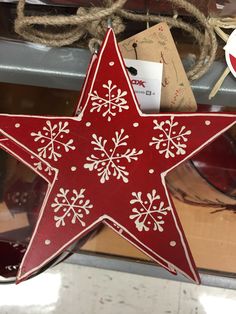 a red and white wooden star with snowflakes hanging from it's side