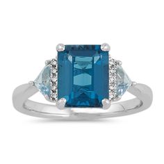 One emerald cut London blue topaz gemstone (approx. 3.06 carats) highlights this exquisite ring. Two trillion sky blue topaz gemstones (approx. .47 carat TW)  and 10 round diamonds (approx. .05 carat TW) make brilliant accents. Crafted from quality 14 karat white gold  this bold ring measures 9.5mm at the center and has a total gem weight of approximately 3.58 carats. Riley Blue, Topaz And Diamond Ring, Bold Rings, Gold Cocktail Ring, Semi Precious Jewelry, Platinum Jewelry, Natural Diamond Ring, White Gold Chains, Gold Cocktail