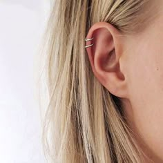 a close up of a person's ear wearing a pair of tiny gold hoop earrings