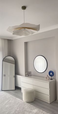 a bedroom with white furniture and round mirrors