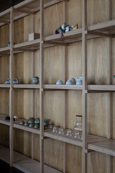 wooden shelves filled with glass vases and bowls on them, all lined up against the wall