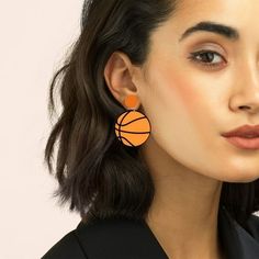 a close up of a person wearing earrings with an orange ball on it's ear