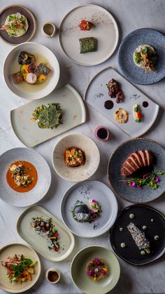 a table topped with lots of plates filled with different types of food and garnishes