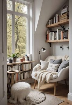 a white chair sitting in front of a window next to a book shelf filled with books