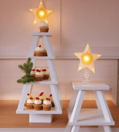 cupcakes are arranged in three tiered trays with lights on top and below them