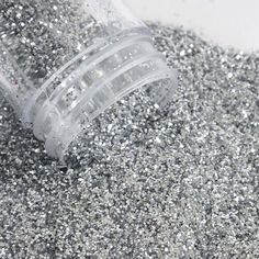 a bottle filled with silver glitter sitting on top of a pile of sand and gravel