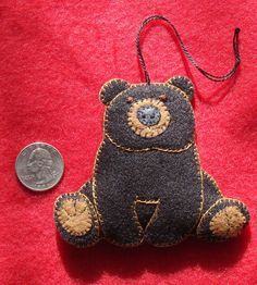 a brown teddy bear sitting next to a coin on a red surface with a string