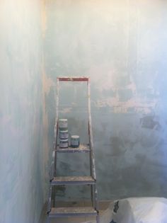 a ladder in the corner of a room with paint on it