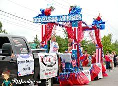 a parade float with an american flag theme and people walking down the street in front of it