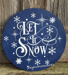 a sign that says let it snow on the side of a wooden fence with snowflakes