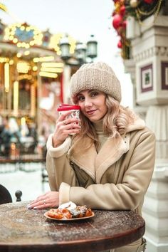 a woman sitting at a table with a plate of food in front of her and holding a cup