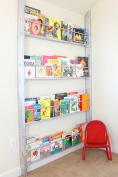 a red chair sitting in front of a bookshelf filled with children's books