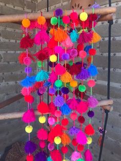 a multicolored mobile with pom - poms hanging from it's sides