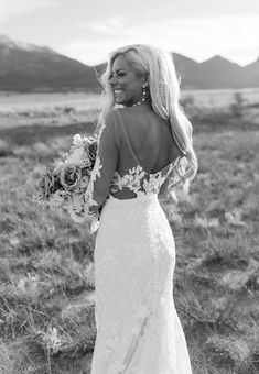 a woman in a wedding dress is walking through the desert with her back to the camera