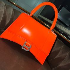 Authentic Balenciaga Bag Day Glow Orange Brand Spanking New Never Used **Missing Long Orange Strap*** Hourglass Small Handbag In Orange Shiny Box Calfskin, Aged Silver Hardware Dimensions : L9 X H5,9 X W3,9 Inch Shiny Box Calfskin Handbag Curvilinear Base One Handle Studded Magnet Closure Tone-On-Tone B Logo Hardware 1 Back Pocket 1 Inner Zipped Pocket Nappa Lambskin Lining Made In Italy Wipe With A Soft Cloth Material: 100% Calfskin Luxury Orange Crossbody Satchel, Orange Top Handle Shoulder Bag With Dust Bag, Orange Top Handle Bag With Dust Bag, Modern Orange Evening Bags, Modern Party Bags With Branded Hardware, Luxury Orange Bags With Top Carry Handle, Designer Orange Satchel Shoulder Bag, Chic Orange Satchel For Evening, Chic Orange Evening Satchel