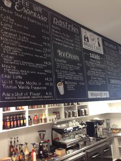 a restaurant menu hanging on the wall next to a coffee machine and other items in front of it