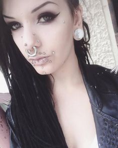 a woman with long black hair and piercings on her nose is posing for the camera