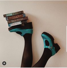 a pair of black and turquoise high heeled shoes with books stacked on top of them