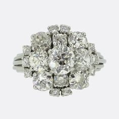 Here we have a truly beautiful old cut diamond ring dating back to the mid 20th century. The ring features a raised central old cut diamond that weighs approximately 1.0 carat and is surrounded by 18 slightly smaller old cuts. In total it plays host to an impressive 4.50 carats of diamonds that are well matched for colour and clarity and give off a spectacular sparkle. The ring is perfect for evening wear and would draw attention on any occasion. It is crafted in platinum and the shoulders are r Antique Brilliant Cut Diamond White Cluster Ring, Vintage Diamond White Cluster Ring With Diamond Cut, Vintage Diamond Cluster Ring With Diamond Cut, Vintage Diamond Ring With Rose Cut Diamonds For Anniversary, Vintage Rose Cut Round Diamond Ring, Vintage Rose Cut Diamond Ring For Anniversary, Vintage Diamond White Cluster Ring With Round Cut, Vintage Cluster Ring In Diamond White With Round Cut, Vintage White Cluster Ring With Rose Cut Diamonds