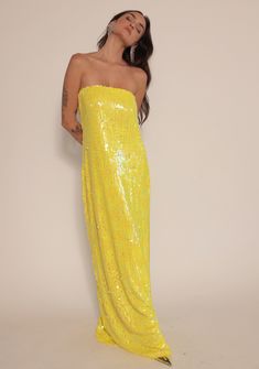 a woman in a yellow sequin dress poses for the camera with her arms behind her back