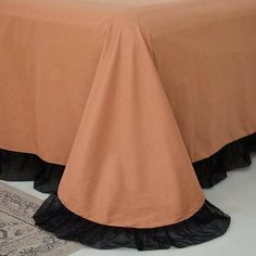 a bed with a brown bedspread and black ruffles on the bottom