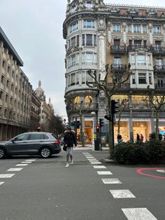 a person crossing the street in front of a building with many windows and balconies