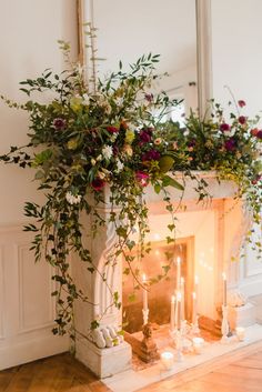 a fireplace decorated with greenery and candles