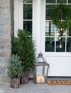 two potted plants and a lantern on the front porch