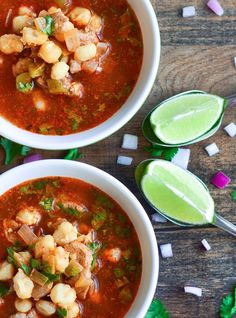 two white bowls filled with soup and garnished with cilantro, lime wedges