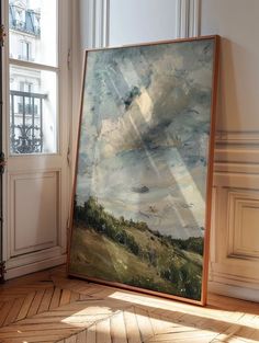 a painting is sitting on the floor in front of a window with sunlight streaming through it