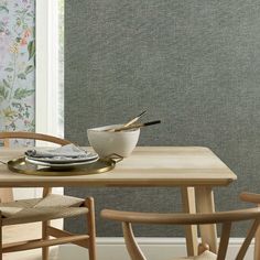 a wooden table topped with a bowl of food next to two chairs and a window