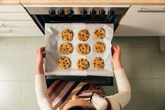 a woman placing cookies on top of an oven