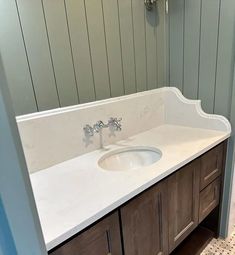 a bathroom sink with two faucets on the counter and wood paneling behind it