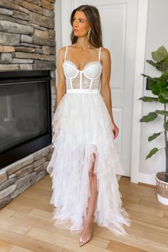 a woman standing in front of a fireplace wearing a white dress