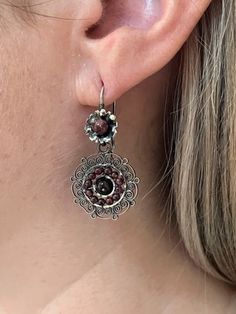 We are excited to feature a collection of Mexican Silver Filigree Earrings from Oaxaca in our store. Each piece is crafted from molten silver, processed and formed into intricate designs, often adorned with exquisite stones. Our artisans, with their skilled hands, create unique pieces that encapsulate a stunning and romantic aesthetic. Adorning these pieces, you're not just wearing jewelry; you're embodying a special, timeless elegance. Materials:  Oxidized Pure 92.5 Sterling Silver Gemstone: Amethyst Drop Length: 1 1/2" long, 1" wide Closure: Ear Wire Traditional Brown Teardrop Jewelry, Traditional Brown Drop Earrings Jewelry, Artisan Round Filigree Jewelry, Traditional Brown Drop Earrings, Traditional Brown Round Earrings, Traditional Brown Dangle Jewelry, Adjustable Filigree Earrings, Artisan Pierced Earrings For Festival, Traditional Brown Nickel-free Jewelry